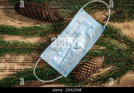 Vue de dessus deux cônes de pin, et masque médical sur un fond en bois brun avec des branches de pin Banque D'Images