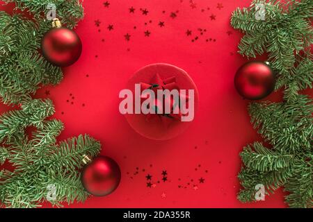 Composition de Noël en cadeau de noël, branches de pin, boules sur surface rouge. Joyeux noël et bonne année concept. Flat lay, vue de dessus Banque D'Images