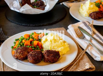 boulettes de viande frites avec purée de pommes de terre et pois beurrés et carottes légumes servis sur une assiette Banque D'Images