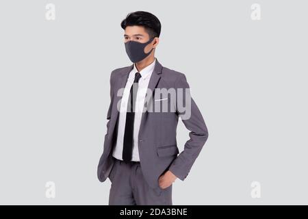 Portrait jeune homme d'affaires asiatique en costume portant un masque de protection pour Covid-19 isolé sur fond blanc, homme d'affaires et de santé, quaranti Banque D'Images
