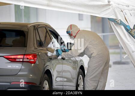 09 novembre 2020, Mecklembourg-Poméranie occidentale, Rostock: Un membre du personnel médical en costume de protection enregistre les données d'une personne qui a conduit en voiture au nouveau centre d'essais, qui a commencé ses activités à la HanseMesse, pour un test de frottis pour le coronavirus. Le centre de frottis est géré par la clinique Südstadt Rostock, le laboratoire médical Rostock et la Croix-Rouge allemande. Le Centre médical de l'Université soutient le centre avec son expérience. Photo: Bernd Wüstneck/dpa-Zentralbild/ZB Banque D'Images