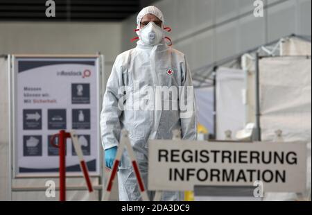 Rostock, Allemagne. 09ème novembre 2020. Un membre du personnel médical en costume de protection se trouve au bureau d'enregistrement et d'information du nouveau centre d'essai de HanseMesse, où les gens peuvent être testés pour le coronavirus s'ils se trouvent dans une voiture. Le centre de frottis est exploité par le Klinikum Südstadt Rostock, le laboratoire médical Rostock et la Croix-Rouge allemande. Le Centre médical de l'Université soutient le centre avec son expérience. Credit: Bernd Wüstneck/dpa-Zentralbild/ZB - ATTENTION: Plaque(s) d'immatriculation a (ont) été pixélisées pour des raisons juridiques/dpa/Alay Live News Banque D'Images