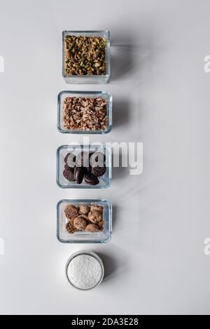 Rangée d'ingrédients dans de petits récipients avec pistache, noix, biscuits et noix de coco déshydratée Banque D'Images