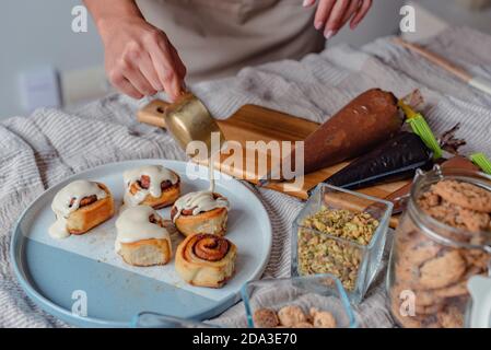 Main d'une femme préparant et décorant des rouleaux de cannelle une casserole ronde Banque D'Images