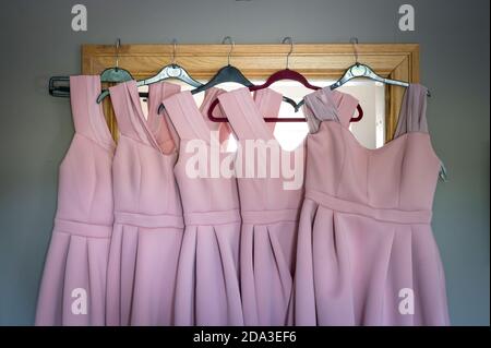 Robes de demoiselles d'honneur roses suspendues sur un miroir de chambre. Banque D'Images