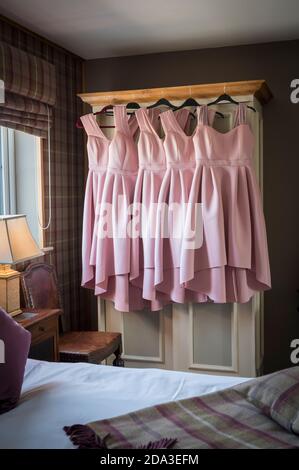 Robes de demoiselles d'honneur roses accrochées à une porte d'armoire dans une chambre. Banque D'Images