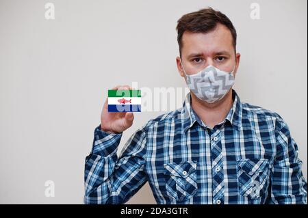 Homme dans le maillot à carreaux montrer Federal Dependencies of Venezuela drapeau carte en main, porter masque de protection isolé sur fond blanc. États-Unis Co Banque D'Images