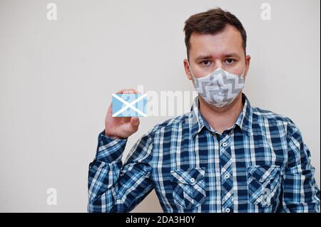 Homme en chemise à carreaux montre San Andrés et Providencia drapeau carte en main, porter masque de protection isolé sur fond blanc. Pays américains Coronavir Banque D'Images