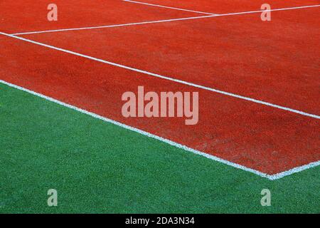 Partie de terrain de tennis rouge utilisé vide avec gros plan sur les lignes blanches Banque D'Images