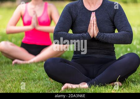 Anonyme mature FIT bonne santé moyenne âge femme professeur de yoga yogi enseigner la jeune femme à pratiquer le yoga à l'extérieur dans un naturel environnement vert tranquille Banque D'Images