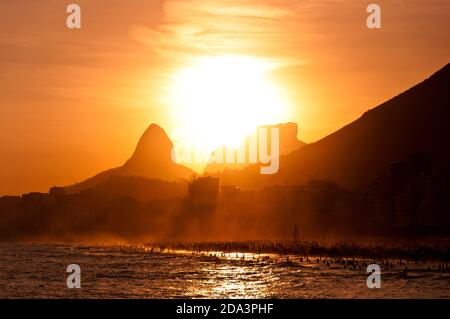 Vue panoramique sur le coucher du soleil à Copacabana Beach, le soleil descend derrière les montagnes, Rio de Janeiro, Brésil Banque D'Images