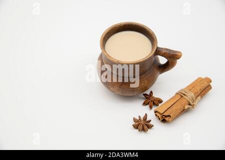 Mug en argile brune avec une boisson et diverses épices sur fond blanc. Banque D'Images