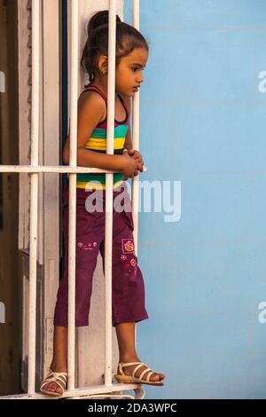 Cuba, Trinidad, fille regardant par la fenêtre grill à Casa de Culture Banque D'Images