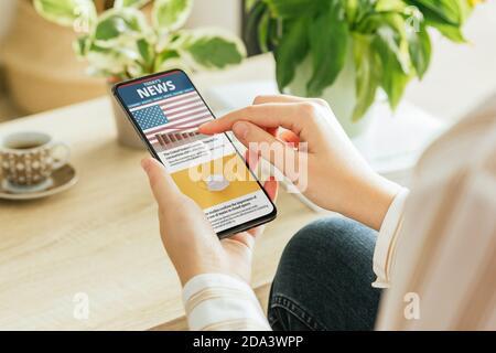 Photo d'une femme lisant des nouvelles sur son téléphone dans le salon Banque D'Images