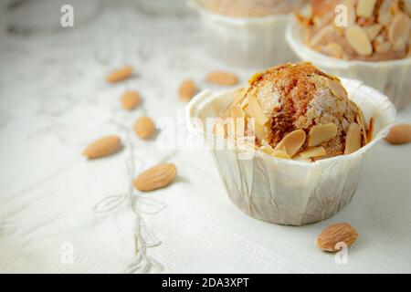 Gros plan de trois muffins sur une table en bois avec une nappe blanche et plusieurs amandes. Photographie horizontale et espace de copie Banque D'Images