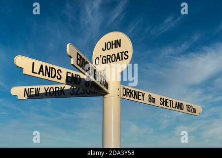 New John O'Groats signe avec le kilométrage à Orkney, Shetland, Lands End, Édimbourg et New York. Isolé contre un ciel bleu et un fond de nuage clair Banque D'Images