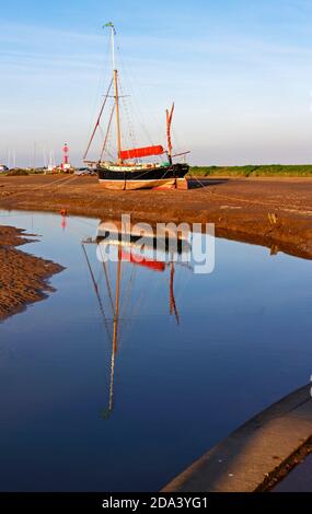 Une vue de la Sailing Barge Juno a été enachée à basse eau avec réflexion dans le port de North Norfolk à Blakeney, Norfolk, Angleterre, Royaume-Uni. Banque D'Images