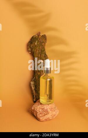 Sérum ou huile essentielle cosmétique en flacon de verre avec une pipette sur podium en pierre sur fond beige avec des feuilles de fougères ombragées. Maquette, vue avant Banque D'Images