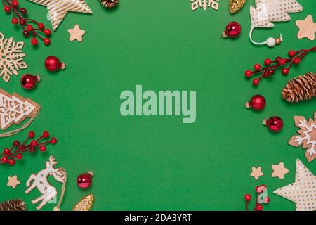 Cadre de Noël avec décorations en verre, textile et bois, cônes de pin, baies sur fond vert pastel. Vue de dessus de la couche à plat, espace de copie Banque D'Images