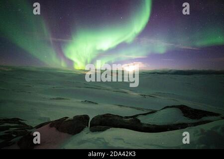 Paysage enneigé éclairé par la lune dans le ciel étoilé pendant les aurores boréales, Skarsvag, Nordkapp, Troms og Finnmark, Norvège Banque D'Images