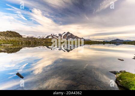 Ciel nuageux au-dessus du sommet de la montagne de Tresero se reflétant dans le lac Manzina, Valfurva, Valtellina, province de Sondrio, Lombardie, Italie Banque D'Images