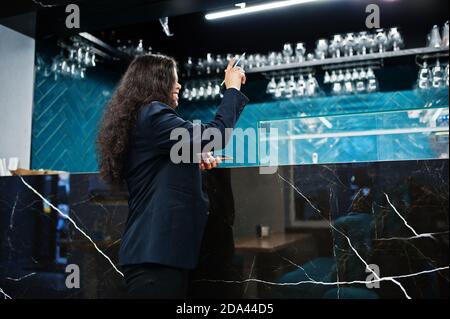 Magnifique femme indienne porte formelle posant au café près du comptoir du bar et appelant le barmen. Banque D'Images
