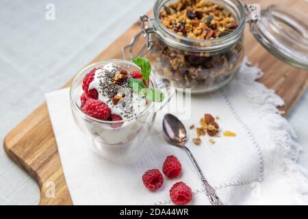 Granola dans un pot et dans une tasse avec yaourt et framboise vue sur le dessus. Le granola est un petit déjeuner et un snack composé de flocons d'avoine, de noix, de miel, qui est cuit jusqu'à ce qu'il soit doré Banque D'Images