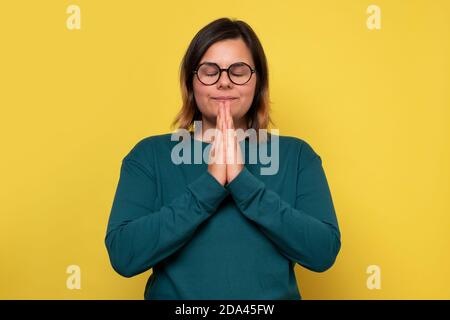 La bonne femme caucasienne garde les paumes ensemble priant. Banque D'Images