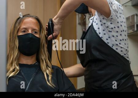 Coiffeur professionnel, styliste faisant la coiffure spéciale, redressant les cheveux longs beaux avec les cheveux Fers à repasser dans le salon de coiffure.Pretty femme client Banque D'Images