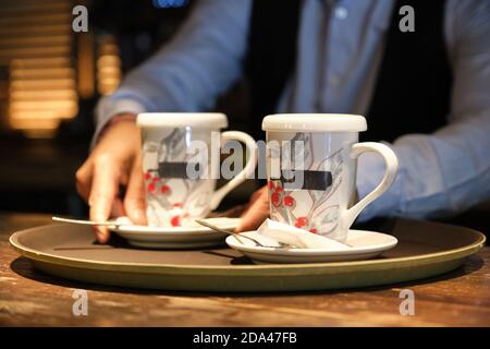 Un serveur mettant deux tasses de thé sur un plateau. Restaurants concept de service. Banque D'Images