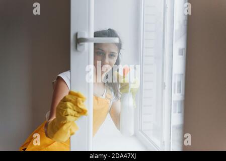 Femme de ménage dans les fenêtres de nettoyage jaune uniforme. Conception de rénovation de maison Banque D'Images