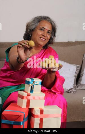 Femme indienne en saree / sari avec laddu et des boîtes cadeaux sur diwali / festival. Banque D'Images