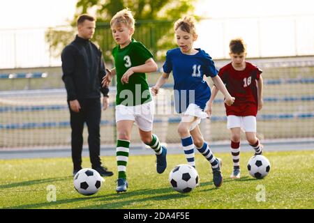 Jeunes garçons en train de courir sur l'entraînement de football. Happy Kids sur les sports de football. Enfants dans des chemises en jersey colorées Banque D'Images