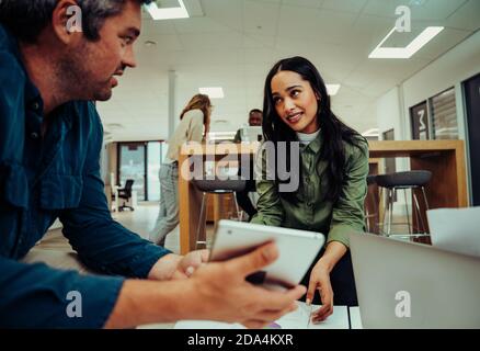 Une femme de race mixte donne des conseils à l'homme d'affaires pour s'améliorer son projet assis dans le salon de bureau Banque D'Images