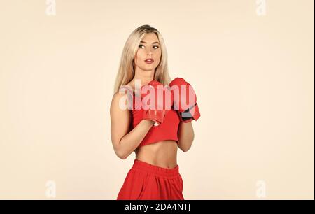 Pleine d'énergie. Blonde boxer femme. Coup de pied. Confiance jeune sportswoman posant dans des gants de boxe. Belle femme avec des gants de boxe rouges. Jeune femme de sport en combinaison et gants de boxe. Banque D'Images