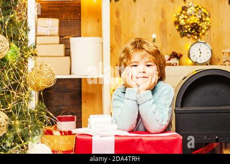 Petits enfants adorables célébrant Noël. Portrait du père Noël avec un énorme cadeau rouge regardant l'appareil photo. Bonne Année. Service de livraison en hiver pour les enfants Banque D'Images