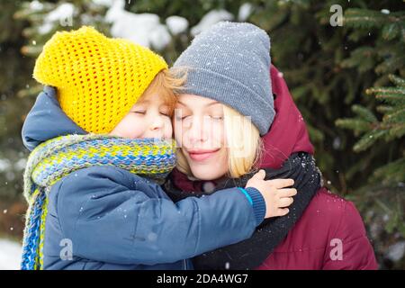 Une jeune maman enhardit son joli enfant. Mère marche avec son petit fils dans une forêt en hiver. Vacances d'hiver. Belle nature d'hiver. Banque D'Images