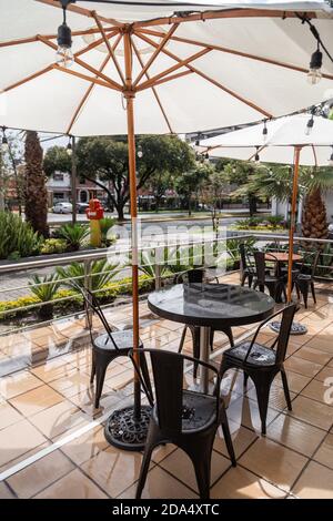 terrasse de restaurant avec une table, des chaises et des parasols, en arrière-plan une rue de ville avec des plantes, style moderne Banque D'Images