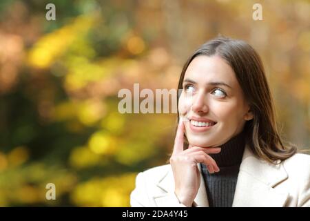 Bonne femme pensant regarder à côté dans une forêt ou parc en automne Banque D'Images