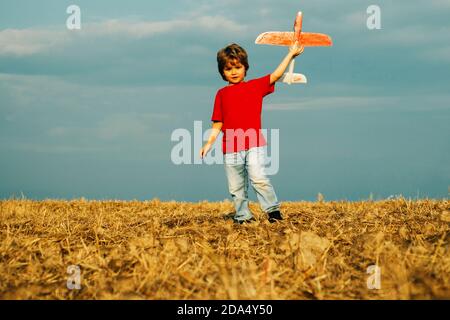 Petit garçon mignon jouant avec un avion jouet. Le concept de la bonté de l'enfant et de l'enfance. Les enfants courent avec le plan sur le champ. Enfant jouant avec le modèle