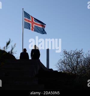 Deux personnes assises près du drapeau islandais au cratère volcanique de Kerid, Grimsnes- og Grafningshreppur, région sud, Islande Banque D'Images