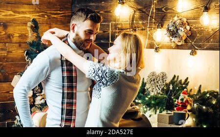 Vacances d'hiver en famille et concept de personnes. Joyeuses vacances. Jeune couple amoureux assis à côté d'un arbre de Noël joliment décoré échangeant Noël Banque D'Images