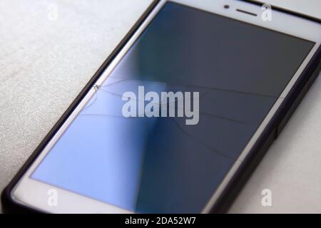 Les zones en surbrillance colorées d'un écran de téléphone mobile cassé dans le reflet de la lumière du jour Banque D'Images