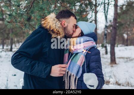 Amoureux couple brûlant des Sparklers et embrassant dans la forêt d'hiver. Fête de Noël et du nouvel an. Vacances d'hiver Banque D'Images