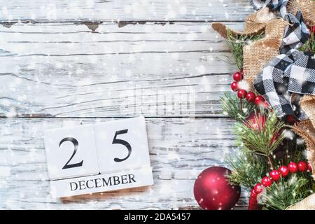 Le 25 décembre l'arrière-plan. Calendrier en bois avec des blocs de la date du 25 décembre pour marquer le Jour de Noël avec lumières bokeh, noir et blanc buffalo vérifier et Banque D'Images