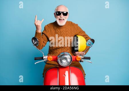 Portrait de son beau joli funky gai gai cheery cool naughty barbu gris-cheveux homme hipster assis sur la mobylette montrant la corne symbole isolé Banque D'Images