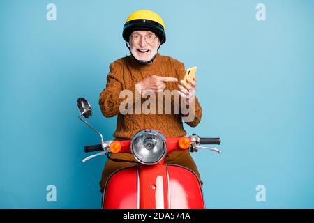 Portrait de son beau beau attrayant gai gai gai heureux barbu homme aux cheveux gris qui roule en mobylette à l'aide d'un dispositif de démonstration de notification isolé Banque D'Images