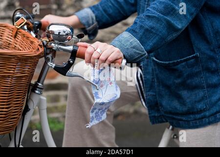 Gros plan d'une femme sur un vélo, tenant un masque facial. Banque D'Images