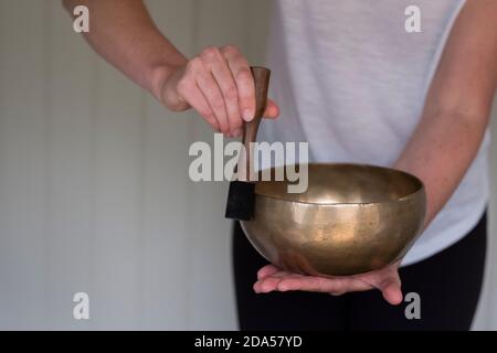 Femme sur un canapé, et une femme thérapeute utilisant le bol de chant tibétain, thérapie sonore Banque D'Images