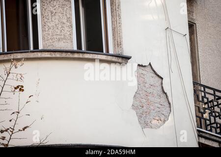 Le plâtre s'écaille d'un mur de façade sur un bâtiment résidentiel, avec un trou laissant la brique visible sur une maison en décade qui a besoin d'être rénové. Photo de Banque D'Images